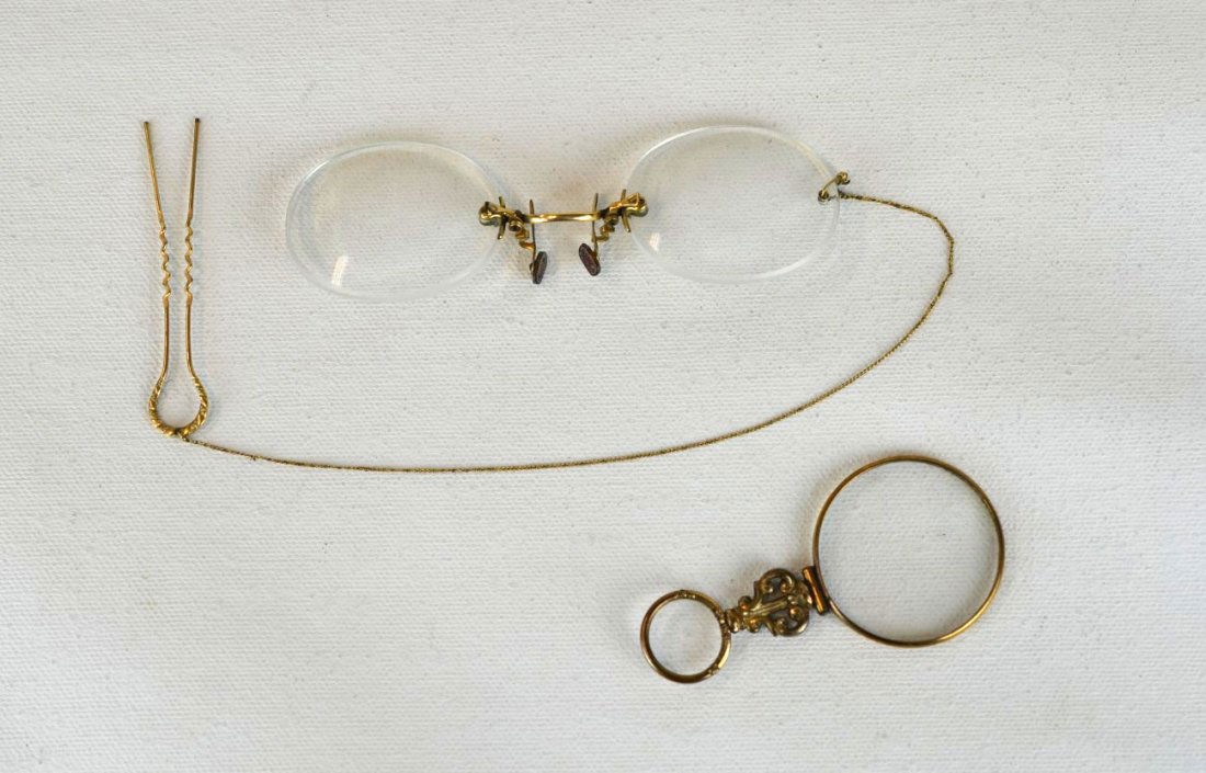 14k Gold Spectacles and Magnifying Glass: 14k Gold bifocals or spectacles, together with a magnifying glass, possibly gold, the bifocals with gold hairpin. Glasses in their original case from store.