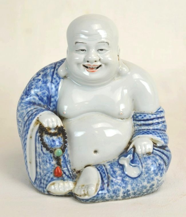 Chinese Blue & White Porcelain Laughing Buddha: Chinese porcelain seated Buddha statue; blue and white painted robes with black, jade, and red prayer beads in left hand. Lips painted red as well. Four character mark imprinted on bottom. 20th c. Hei