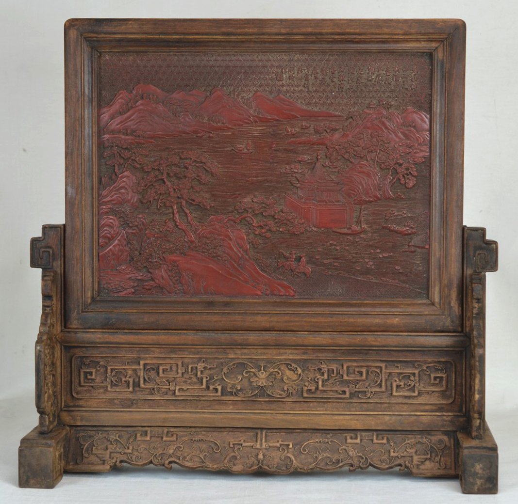 18th c. Cinnabar Huanghuali Chinese Table Screen: Chinese table screen with carved cinnabar plaque of a coastal landscape and wood frame. Sits on ornately carved wooden stand. 18th c. Height 20 1/4'' x Width 21'' x Depth 7 3/4''