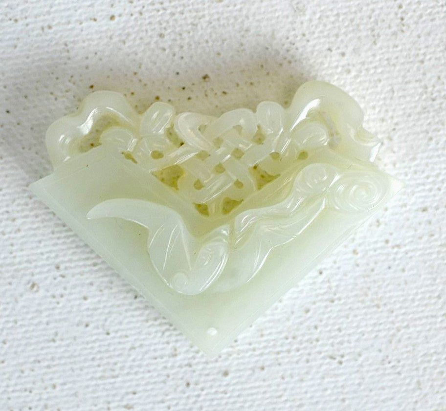 Carved Natural White Jade Pendant: Natural white jade pendant carved with images of fish, a bat, and lattice design with flowers. 1 1/4" x 2"