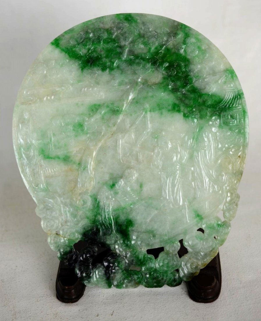 Circular Green Jadeite Plaque: Circular green jadeite plaque carved with the image of three figures under a tree on the obverse, and a bird perched on a mountain peak against a tree on the reverse. The bottom cloud pattern has been