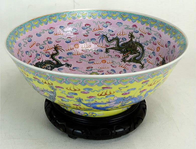 Chinese Porcelain Footed Bowl w/ Dragon Motif: A Chinese porcelain footed bowl decorated with a dragon motif on the interior and exterior. Against a yellow ground on exterior, and a pink ground on interior. Six character copper red mark on bottom.
