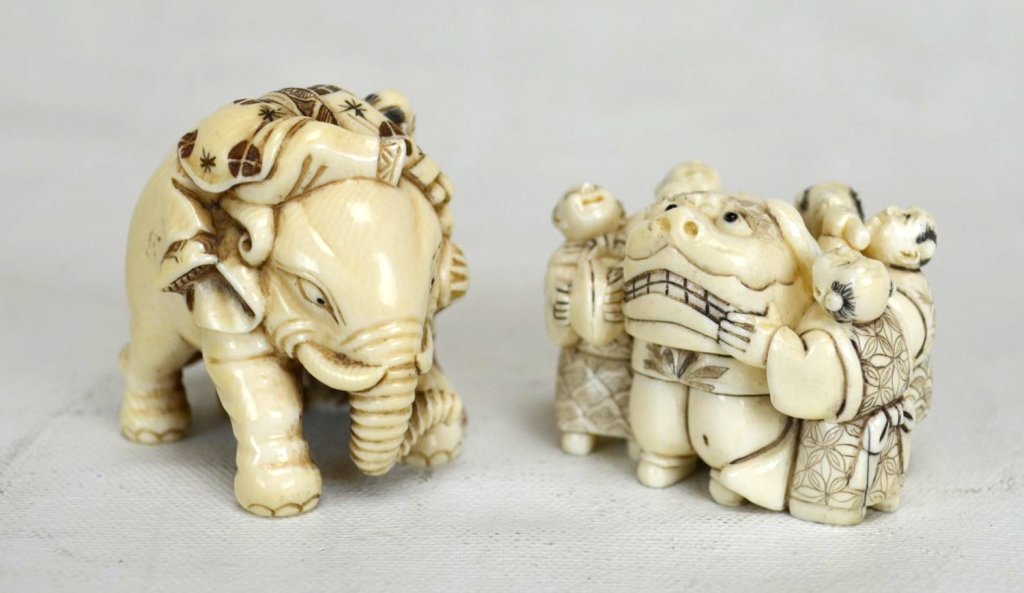 Two Japanese Antique Ivory Carvings: Two Japanese ivory carvings. One with 3 men holding back an elephant, the other with 5 people hanging on to a foo dog. Each approximately 2" x 2" 19th century