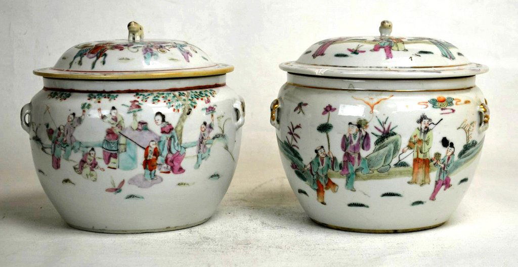 Pair of Chinese Famille Rose Lidded Jars: A pair of lidded jars decorated with scenes of figures outdoors. A gold painted foo dog is atop each lid, and there are two gold painted handles on either side of jars. Six character copper red mark o