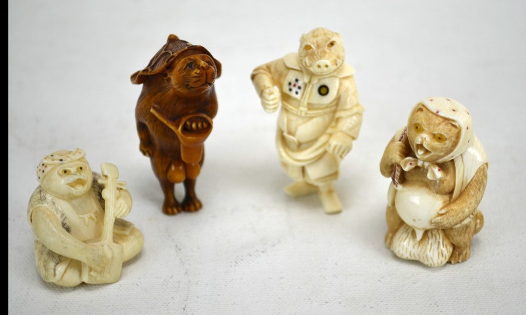 Four Japanese Antique Ivory Netsukes of Animals: Four antique ivory netsukes of animals; a boar dressed as a general, a rat with a hat, a badger with a banjo, and another badger with a bottle on his back. All marked. 19th century. Dimensions: Bigges