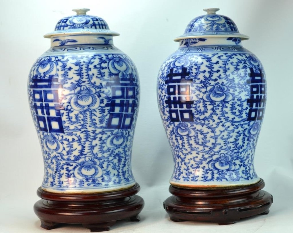 Chinese Porcelain Qing Dynasty Blue & White Lidded: Pair of Chinese porcelain lidded jars decorated in blue and white with the Chinese symbol for double happiness, Qing Dynasty, complete with wooden stand. Several chips to edge of lid, reglued 2" area 