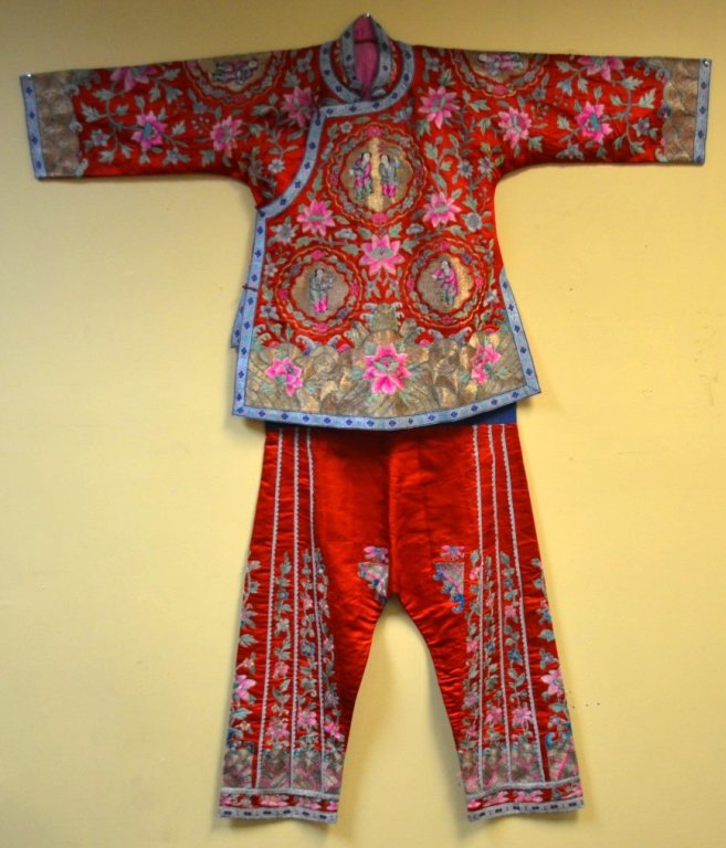 Antique Chinese Silk Embroidered Robe & Pants Set: Antique Chinese silk embroidered robe and pants set, with chains of brightly colored flowers and figures against a bright red ground, highlighted with gold threaded accents.