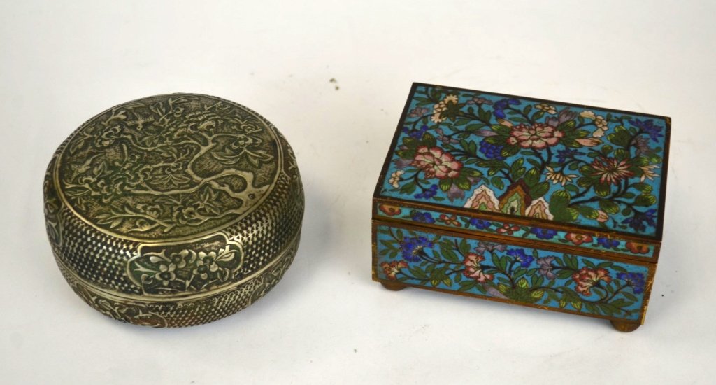 Two Chinese Boxes in Silver and Cloisonne: Two Chinese boxes; round silver box caved with trees, flowers, and birds, together with a cloisonne box, the inside lined in wood, and set atop ball feet. 2 1/2" x 4 1/2" dia. and 2 1/2" x 5 1/2" x 3 