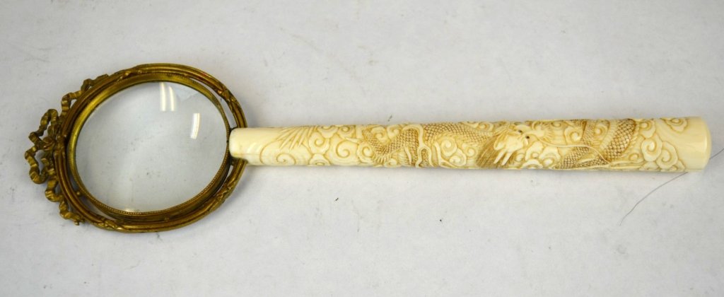 Chinese Magnifying Glass w. Carved Bone Handle: Magnifier with carved bone handle depicting a dragon intertwined with clouds, the glass surrounded by metal with a bow at the top. Handle: 7", Glass: 2 1/4" dia., Overall: 10"
