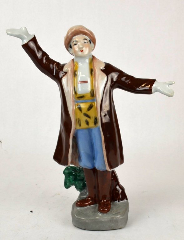Chinese Porcelain Figure of a Man: Chinese porcelain figure of a standing man, wearing a brown coat, boots, and hat. Missing one thumb. 11 3/4" x 10"