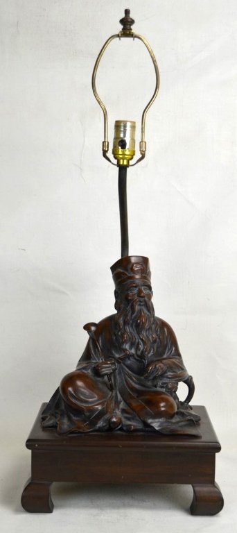 Frederick Cooper Chinese Bronze Seated Fig Lamp: A lamp with a wooden base and a bronze sculpture of a Chinese seated bearded man holding a staff. Frederick Cooper sticker on base of fixture. Base measures 11" x 9" Whole height - 29 1/2" 19th Centur