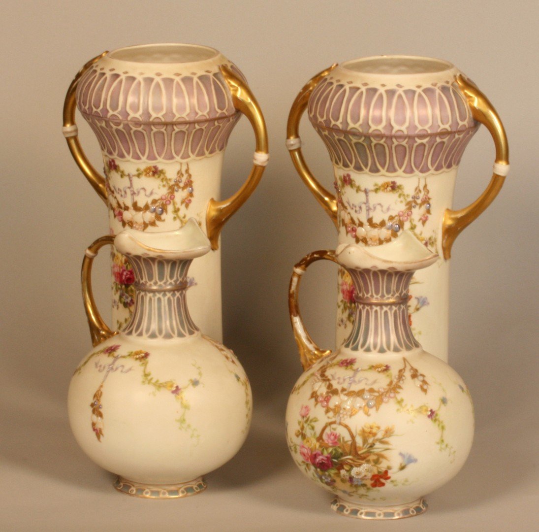 A Pair of Two Handled Vases. Probably Continental,: In the Royal Worcester style, decorated with sprigs of flowers, floral drapes and swags. Gilt twin handles. Some rubbing to gilding otherwise in good condition. 33cm high. And a Pair of Jugs. Probably