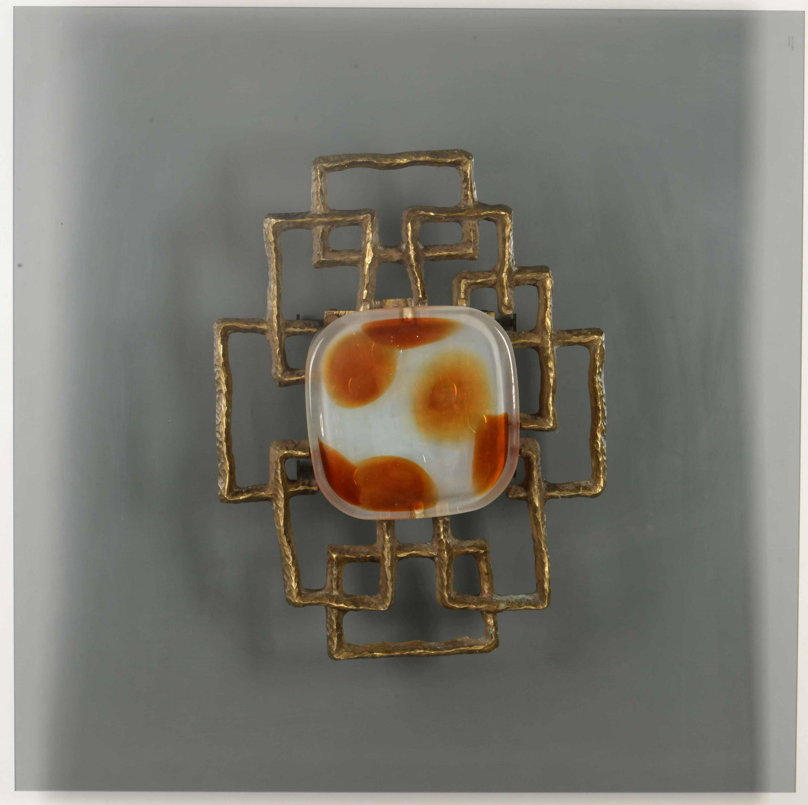 Angelo Brotto,: Pannello decorativo a parete con struttura in fusione di bronzo dorato ed elemento scultoreo centrale in vetro. Prod. Esperia, Italia, 1970 ca. cm 80x80x16; Scultura: cm 50x40x7