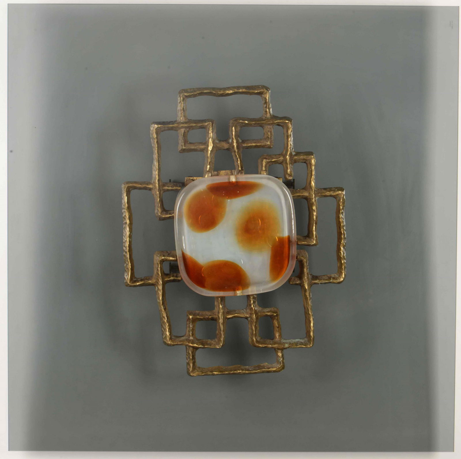 Angelo Brotto: Pannello decorativo a parete con struttura in fusione di bronzo dorato ed elemento scultoreo centrale in vetro., Prod. Esperia, Italia, 1970 ca., cm 80x80x16; Scultura: cm 50x40x7