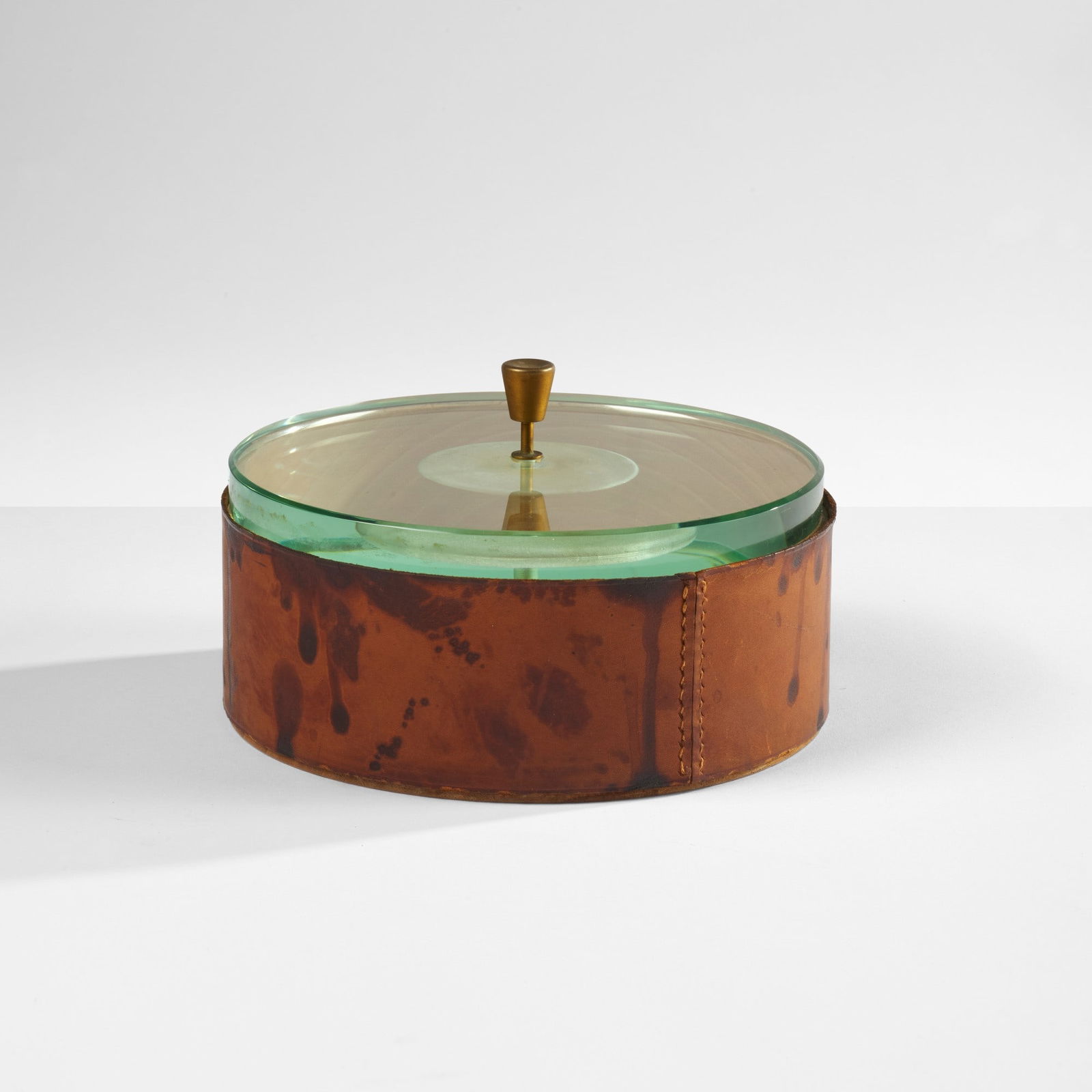 Fontana Arte Scatola mod. 2194: Struttura in legno con rivestimento in cuoio e coperchio in cristallo molato di forte spessore. Maniglia in ottone. Prod. Fontana Arte, Italia, 1950 ca. Catalogo di produzione.