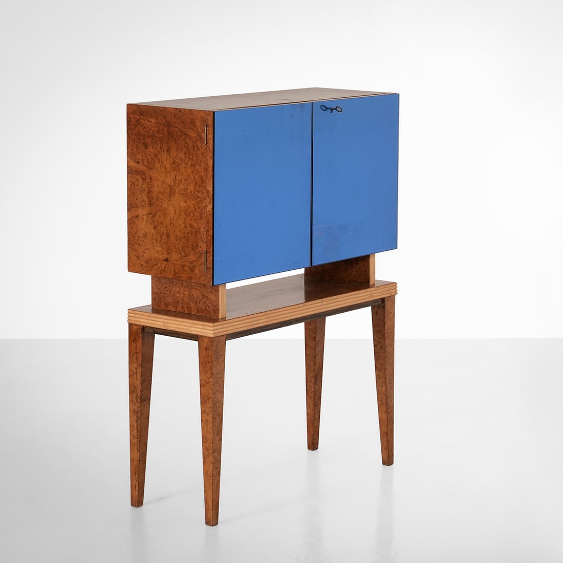 Mobile bar luminoso: Struttura in legno e impiallacciatura di radica. Ante rivestite di vetro colorato. Interni in cristallo molato e specchiato. Prod. Italia, 1950 ca.