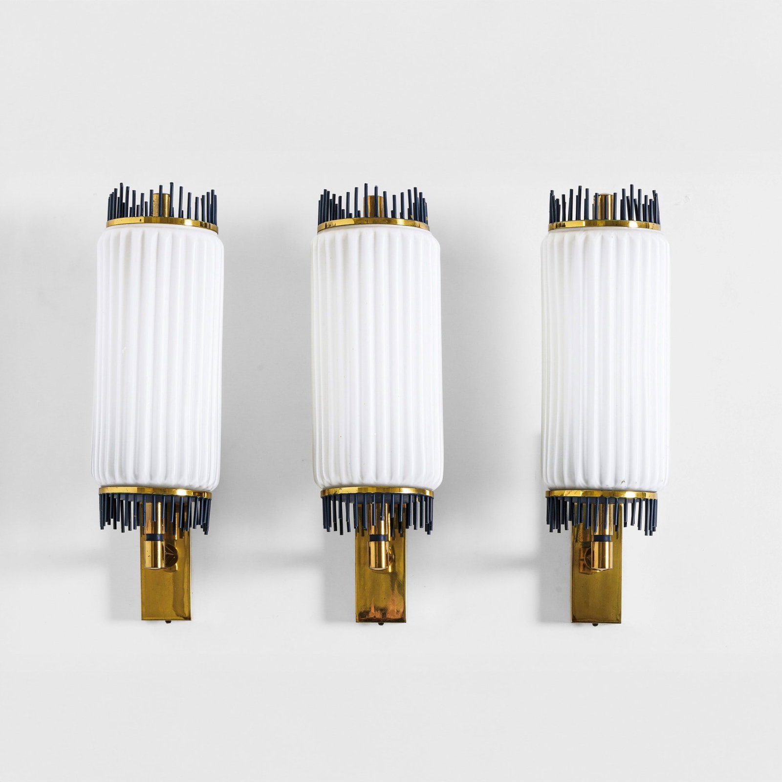 Tre lampade a parete: Struttura in ottone con dettagli in metallo laccato, diffusori in vetro opalino. Prod. Italia, 1960 ca.