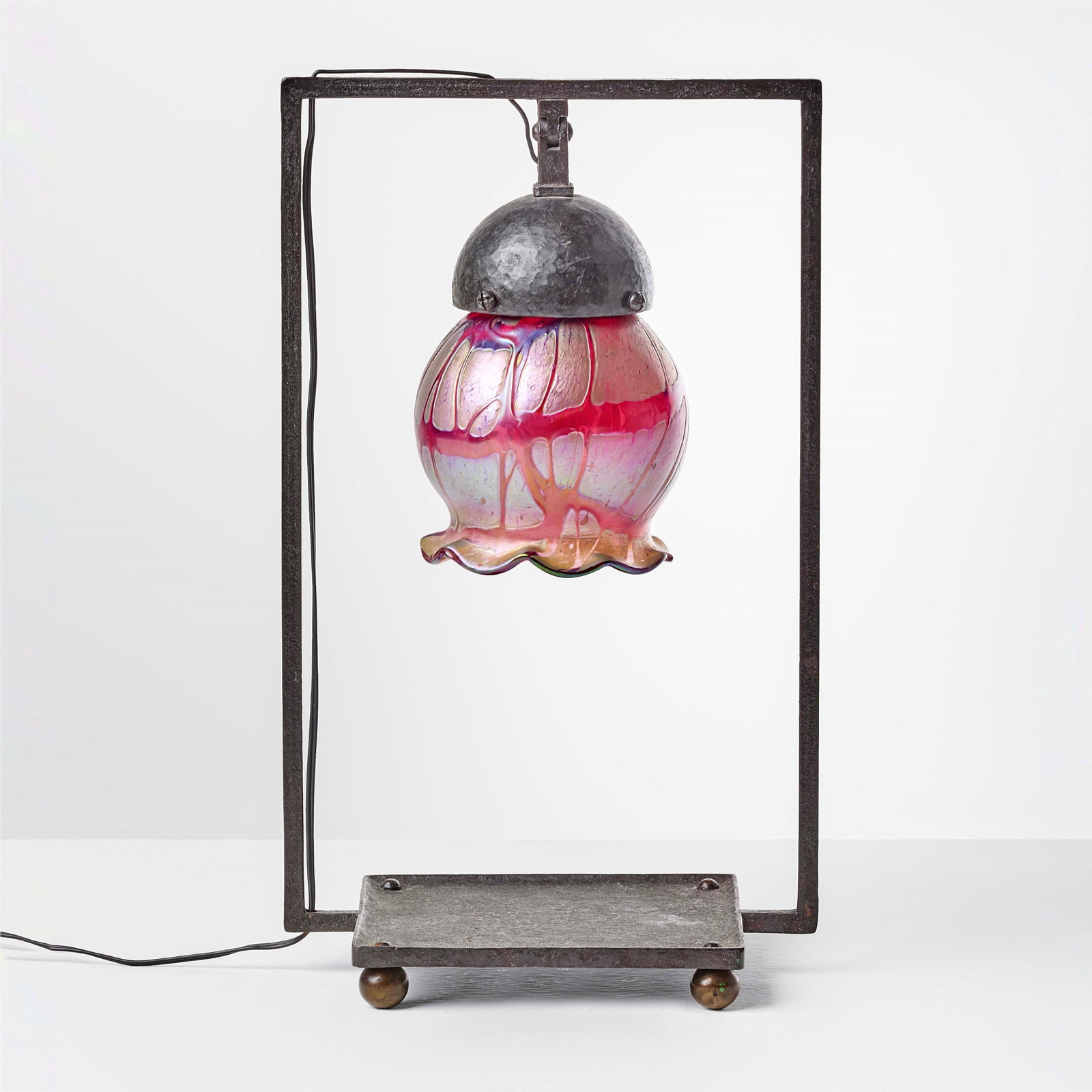 Alessandro Mazzucotelli Table lamp: Wrought iron structure with iridescent glass shade. Signed. Mazzucotelli, Italy, c. 1920. . Measuers: W. 20,5 - D. 15 - H. 34,5 cm