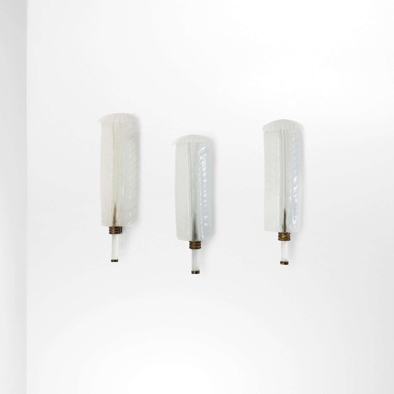 Tomaso Buzzi Tre lampade da parete mod. 413: Struttura in ottone, diffusori in vetro di Murano pulegoso. Dettagli in ottone. Marchio originale. Prod. Venini, Italia, 1933. cm 19x13x52 (a cura di) M. Barovier, C. Sonego, Venini Luce 1921-1985,