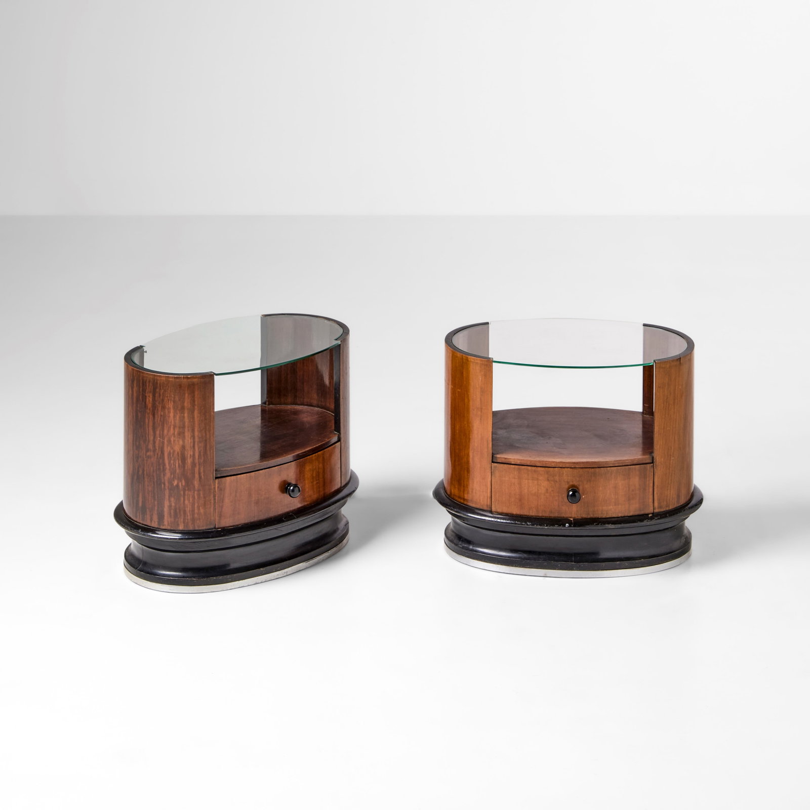 Due comodini: Struttura in legno, legno laccato e piani in cristallo. Dettagli in ottone. Prod. Italia, 1940 ca. . Measuers: W. 56 - D. 36 - H. 49 Cm