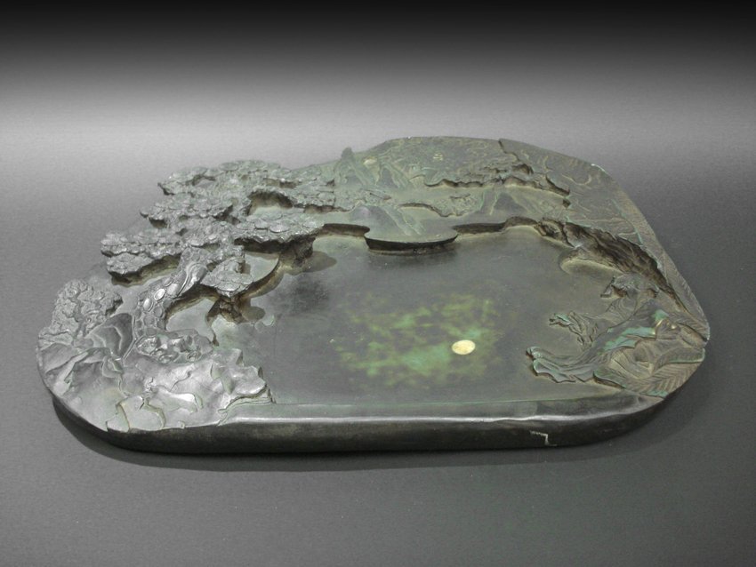 AN ASIAN STYLE NATURAL VIEW INKSTONE.: AN ASIAN STYLE NATURAL VIEW INKSTONE. 14.5" X 11.5" An inkstone carved Asian style natural view including trees, rocks and mountains, the view posited as there is a lake in the middle. There is a yell
