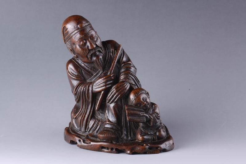 AN QINGCHINESE BAMBOO CARVED OLD MAN WITH A KID.: AN QINGCHINESE BAMBOO CARVED OLD MAN WITH A KID. A bamboo statue showing an old man sitting down and a kid laying his head toward his leg with a book, 19th century. H 18CM X W 7.5cm