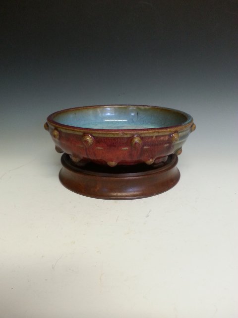 A RED AND BLUE PORCELAIN WASHER: Small washer with outter area attached docs, outside to be red and inside is blue. Crack texture on inner area. A stand is included. D 6"