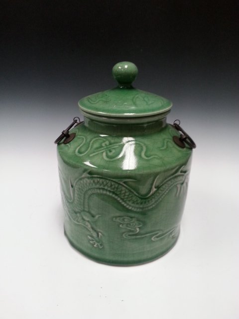 A DRAGON TWIN HANDLE PORCELAIN JAR.: A green porcelain jar with dragon on the body and two handles near by the top. A lid is included and the inside is white. H: 11 in W: 8.2 in (TH)