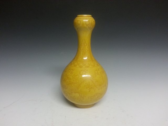 A PORCELAIN YELLOW DRAGON GARLIC BOTTLE: A Garlic bottle with yellow background color. Dragons lightly carved on the body. A six characters "Qianlong" mark on the bottom. H 7"