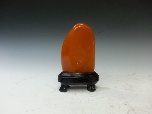 SHOU STONE DECORATION: A shou stone with one side carved to be a man and a building on top. The other side has a lightly carved leaves. A stand is included. H 3" X W 2"