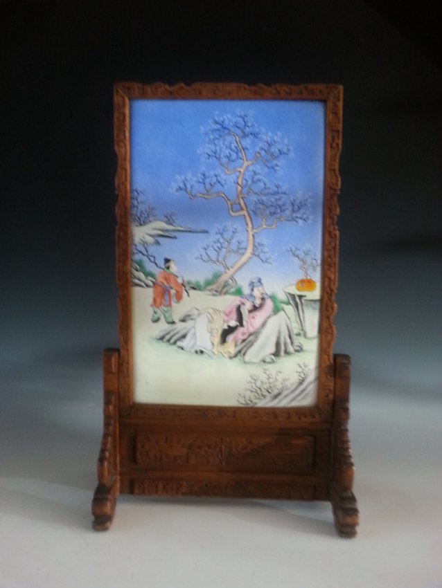 WOODEN TABLE SCREEN WITH PAINTING: This wooden table screen with colorful painting of a man sitting down on a rock along with a kid on a mountain next to the edge. The man seems to be sitting down for relaxing and the kid is holding a