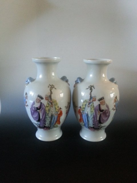 A PAIR OF OLD PORCELAIN MEN PAINTING VASE: This pair of vase has painting of old men on each of them. The old man is holding a holder with his right hand and is talking with another person, there are more people following him. There are two ha