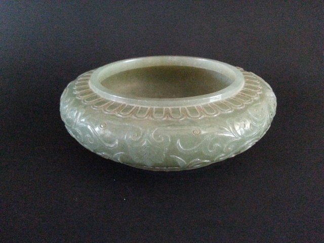 AN CHINESE JADE CARVED WASHER: This jade washer has finely carved pattern of leaves on the outter area. A black mark on the bottom of inner area. A four characters Qianlong mark on the bottom. D 10.3cm