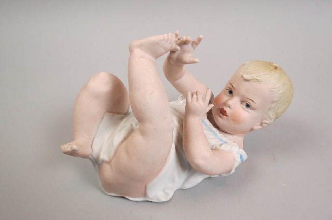 Heubach Bisque Porcelain "Piano Baby" Figurine,: laying on its back, 8 1/2" long, signed, mild flaw lines at neck area, otherwise excellent.