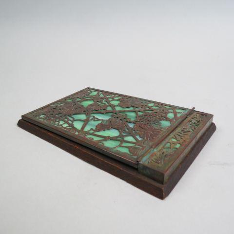 Tiffany Bronze & Glass Note Pad Holder,: grape & vine pattern on green slag, hinged, wooden base, all original, "Tiffany Studios, New York #1022", 5" x 7 1/2".