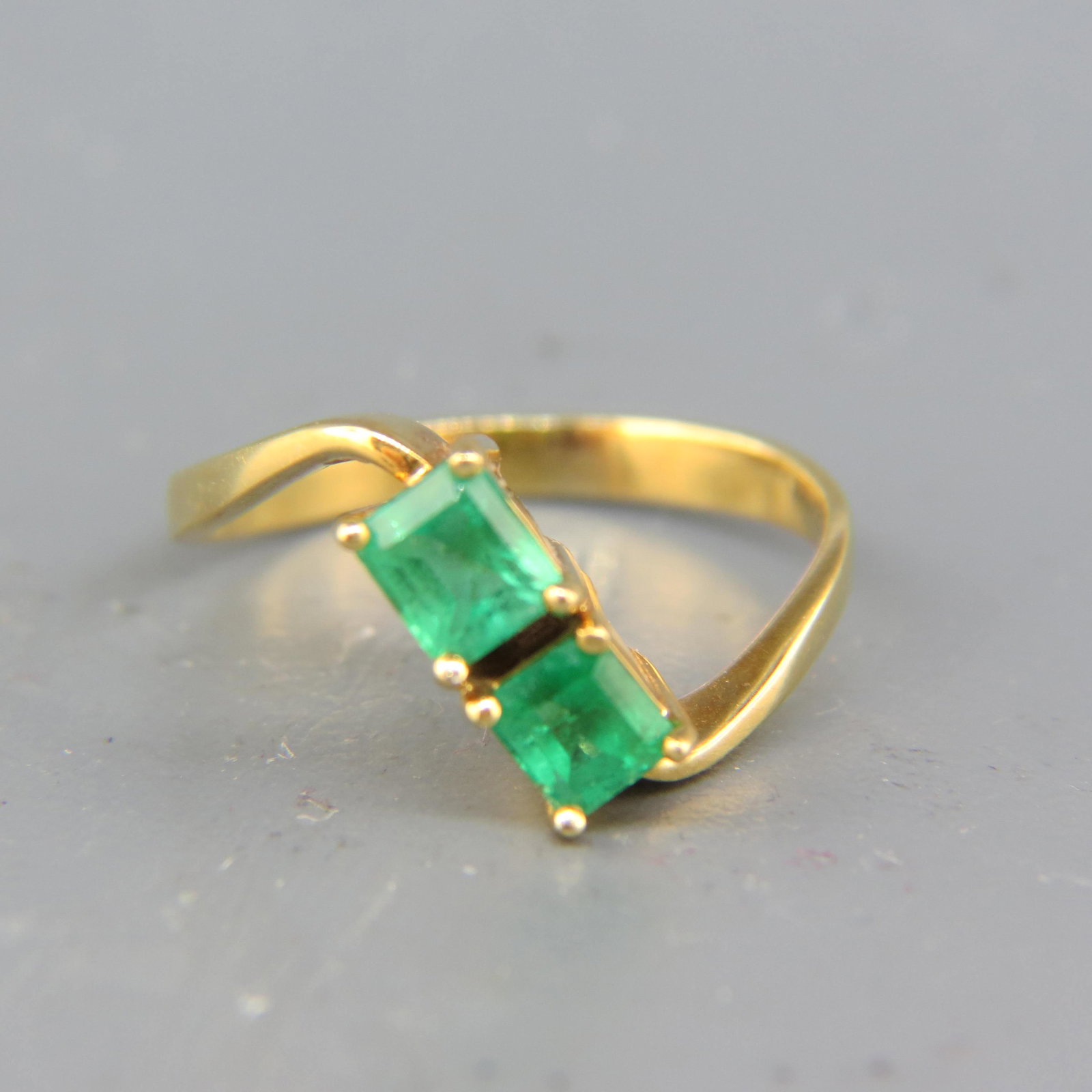Emerald Ring,: two emerald cut gems totaling approx 1 carat in 18K yellow gold, currently size 7.