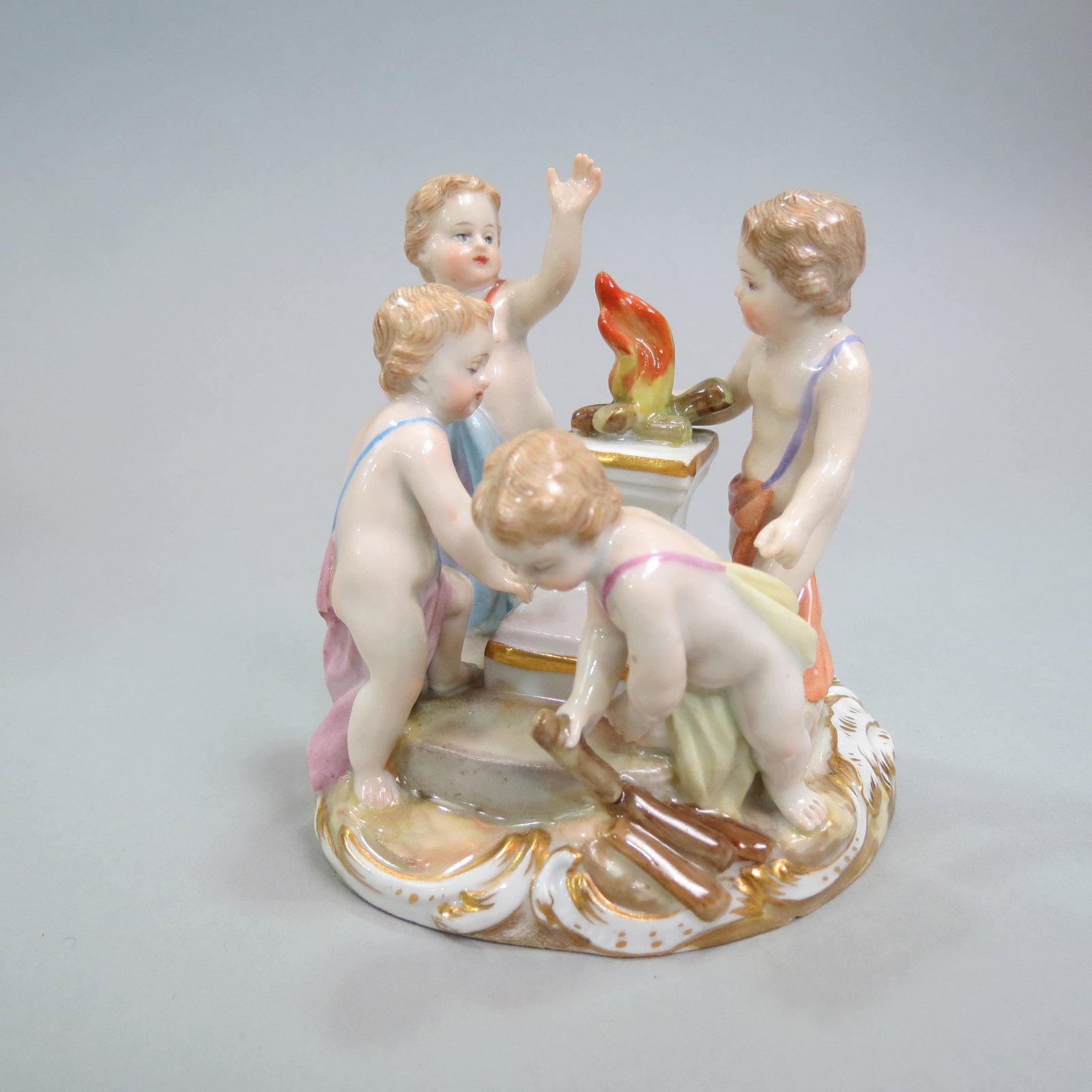 Meissen Porcelain Figurine of Putti at Play,: building a fire upon a garden pedestal, 3 1/2", crossed swords mark, excellent.