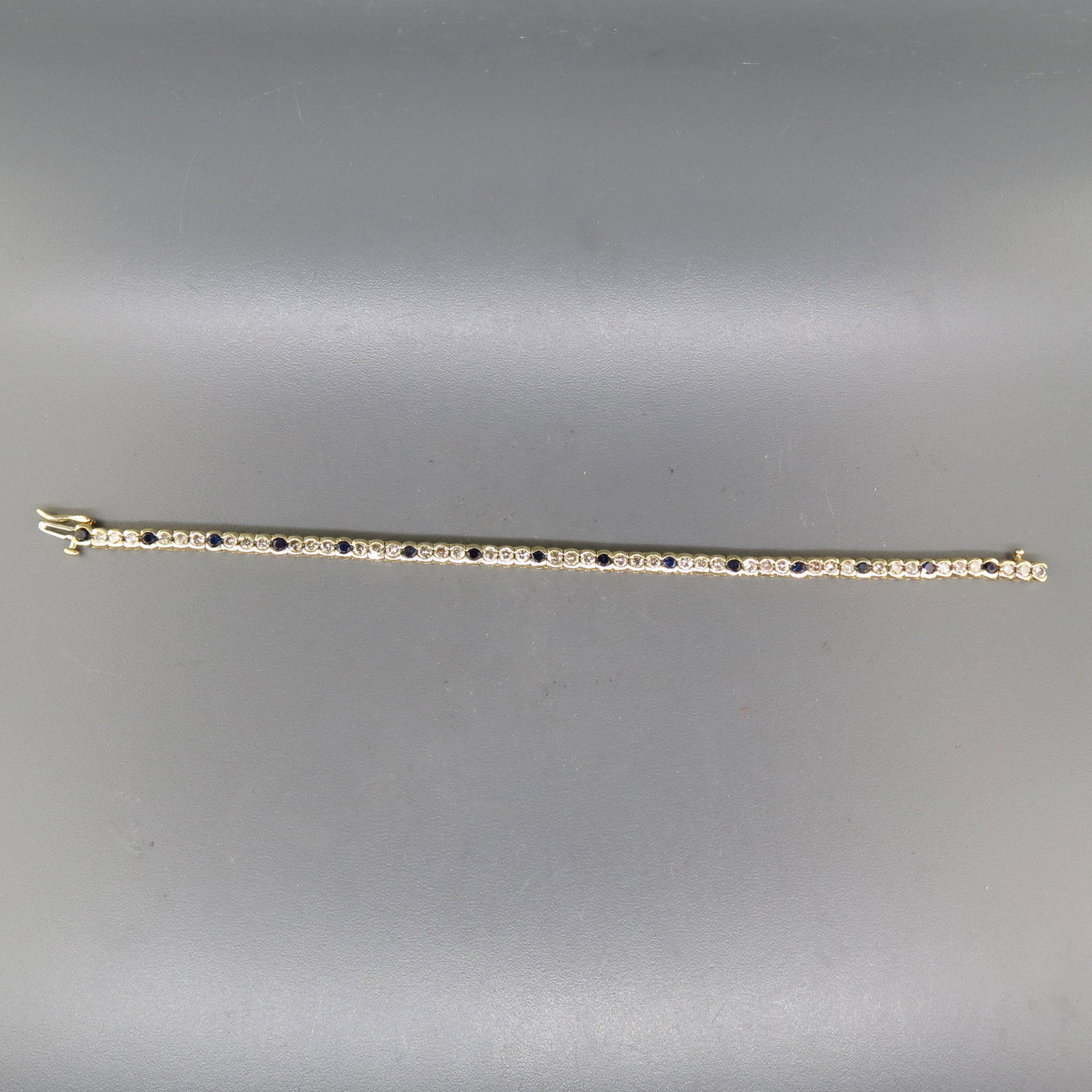 Sapphire & Diamond Bracelet,: 46 round diamonds totaling 3 carats and 15 blue sapphires totaling 2 carats in 14K yellow gold, with appraisal of $5,950.00, 7" long.