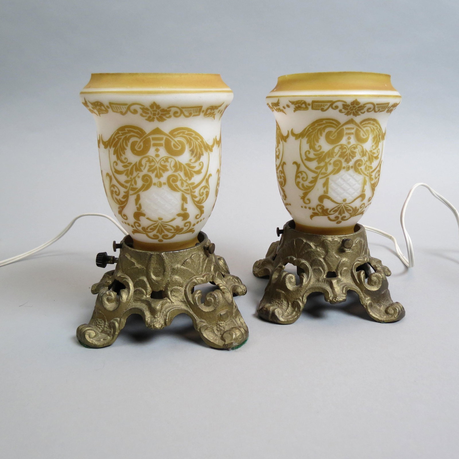 Pair of Steuben Art Glass Acid Cut Back Lamps,: golden brown cameo acid cut designs on white satin with fine cutwork, iridescent interior, on bronzed bases, overall 7 1/2" tall, unsigned, excellent.