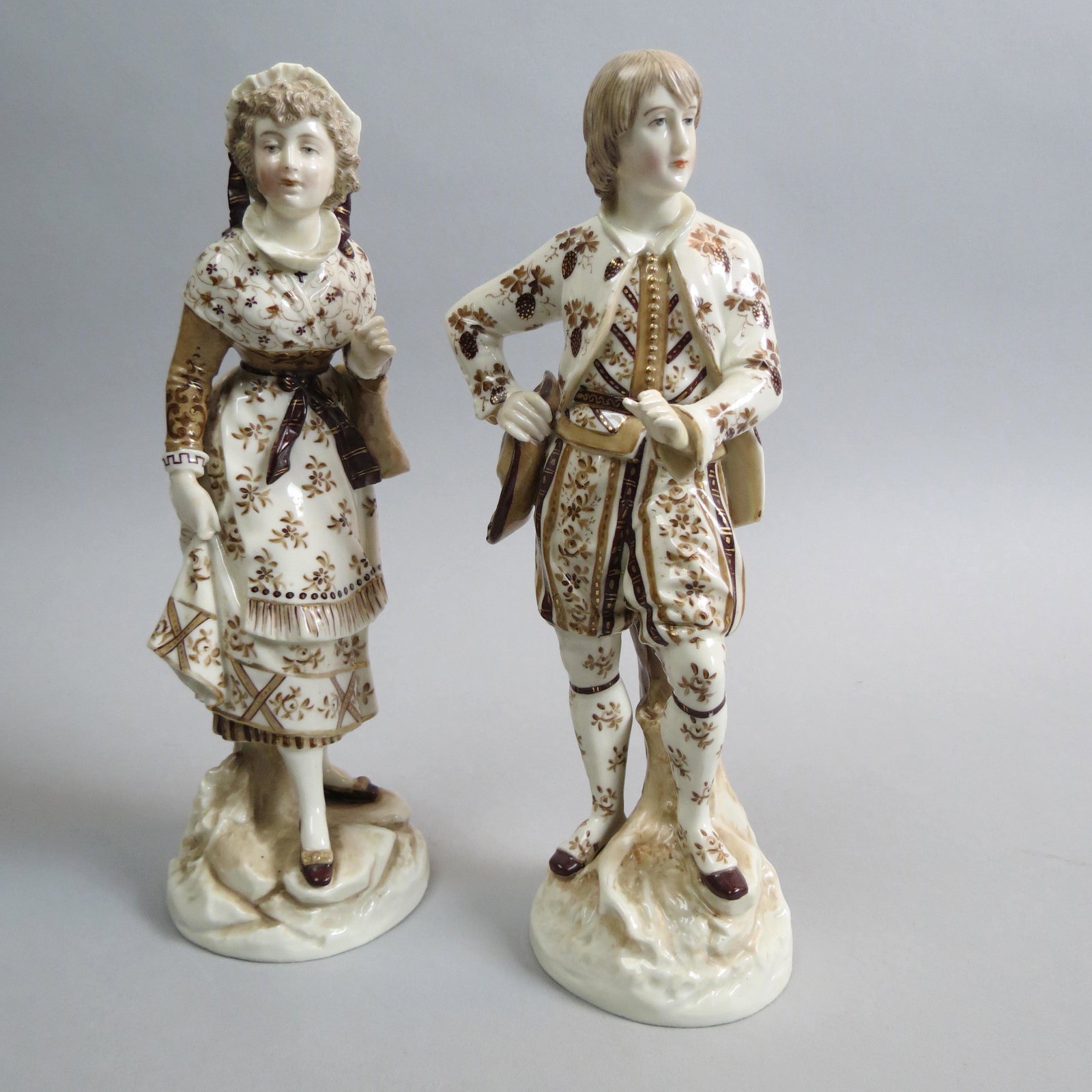 Pair of German Porcelain Figurines of Man & Woman,: man holding a hat, woman with handbag, brown and gold decoration on light cream, signed P.F., 9", excellent.