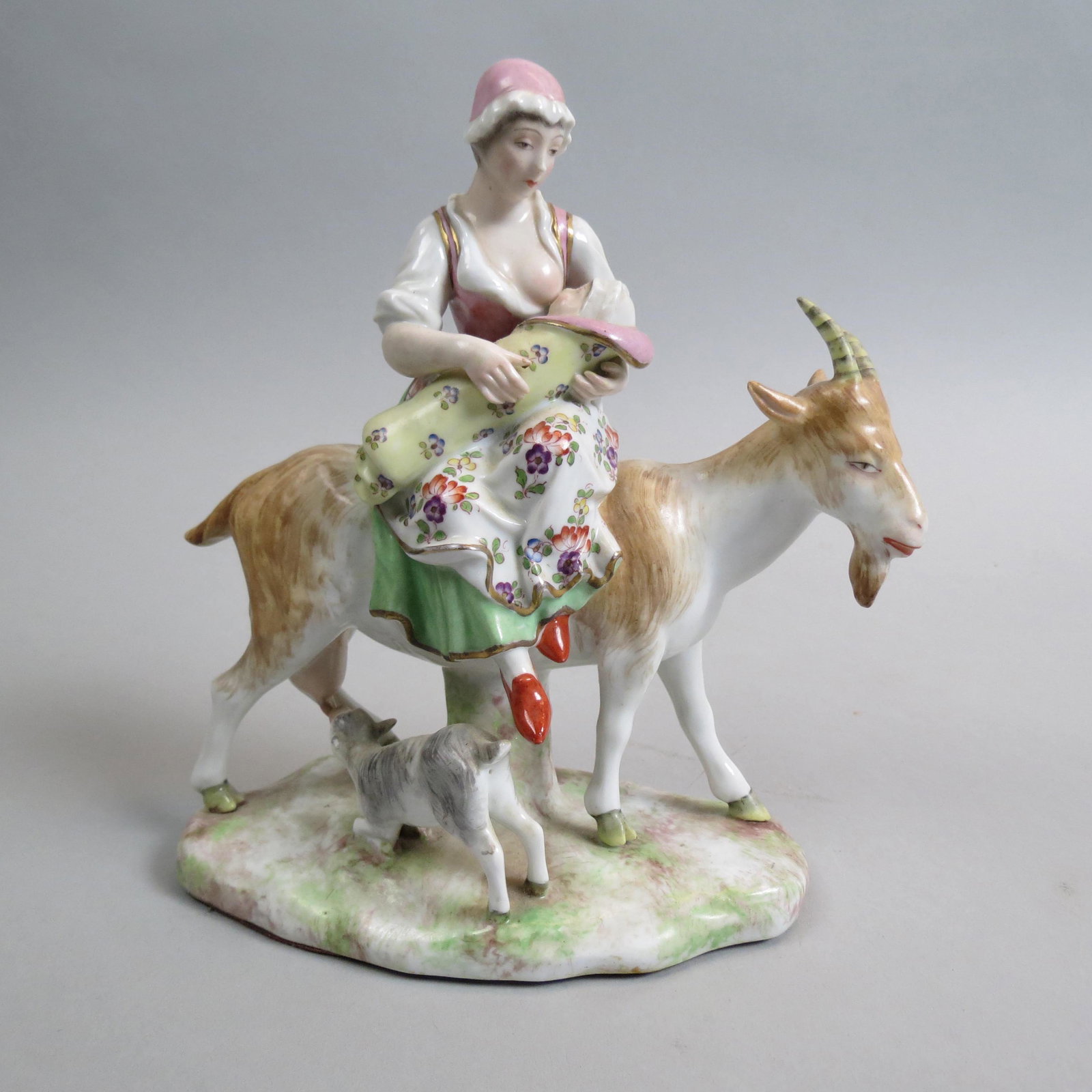 Fine Porcelain Figurine "Nursing Time on the Farm": woman nursing an infant while upon a goat with its kid nursing, finely handpainted, crossed swords mark, 7 1/2", label of Delaux, Rue Royale, Paris, excellent.