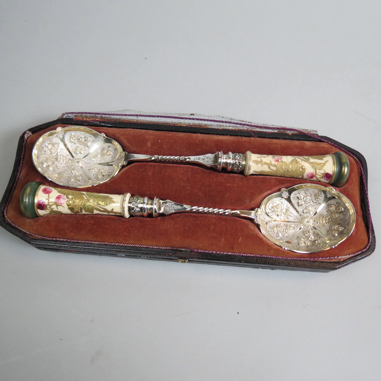 Pair of English Victorian Silverplate Berry Spoons: hand painted porcelain handles with berries and gold leaves, twist handles, elaborate gold wash bowls, 10" long, in original box.