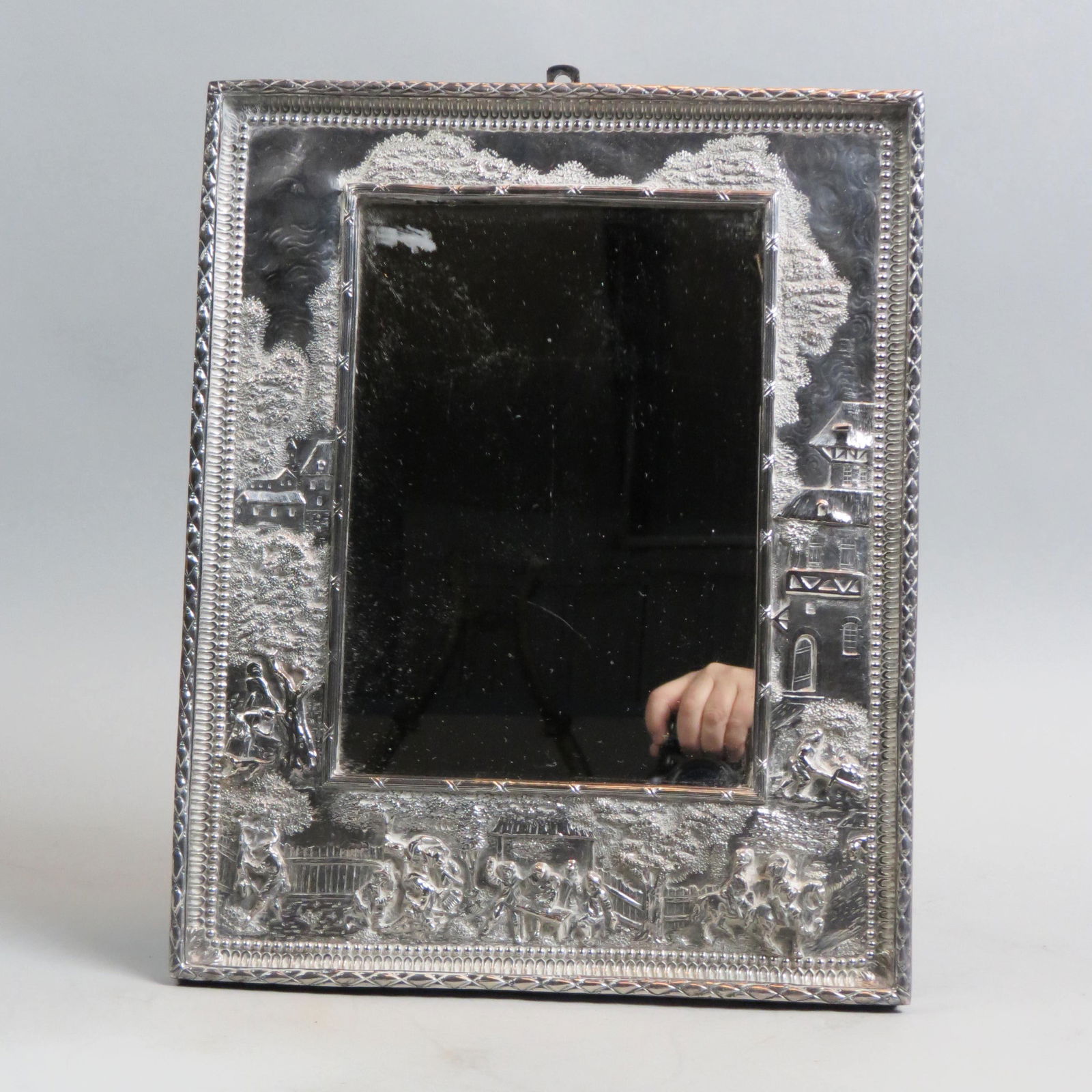 Elaborate Silver on Copper Framed Mirror,: European scenes with cavaliers and villagers, 7" x 9 1/2" mirror, 12" x 14" overall, circa 1900.