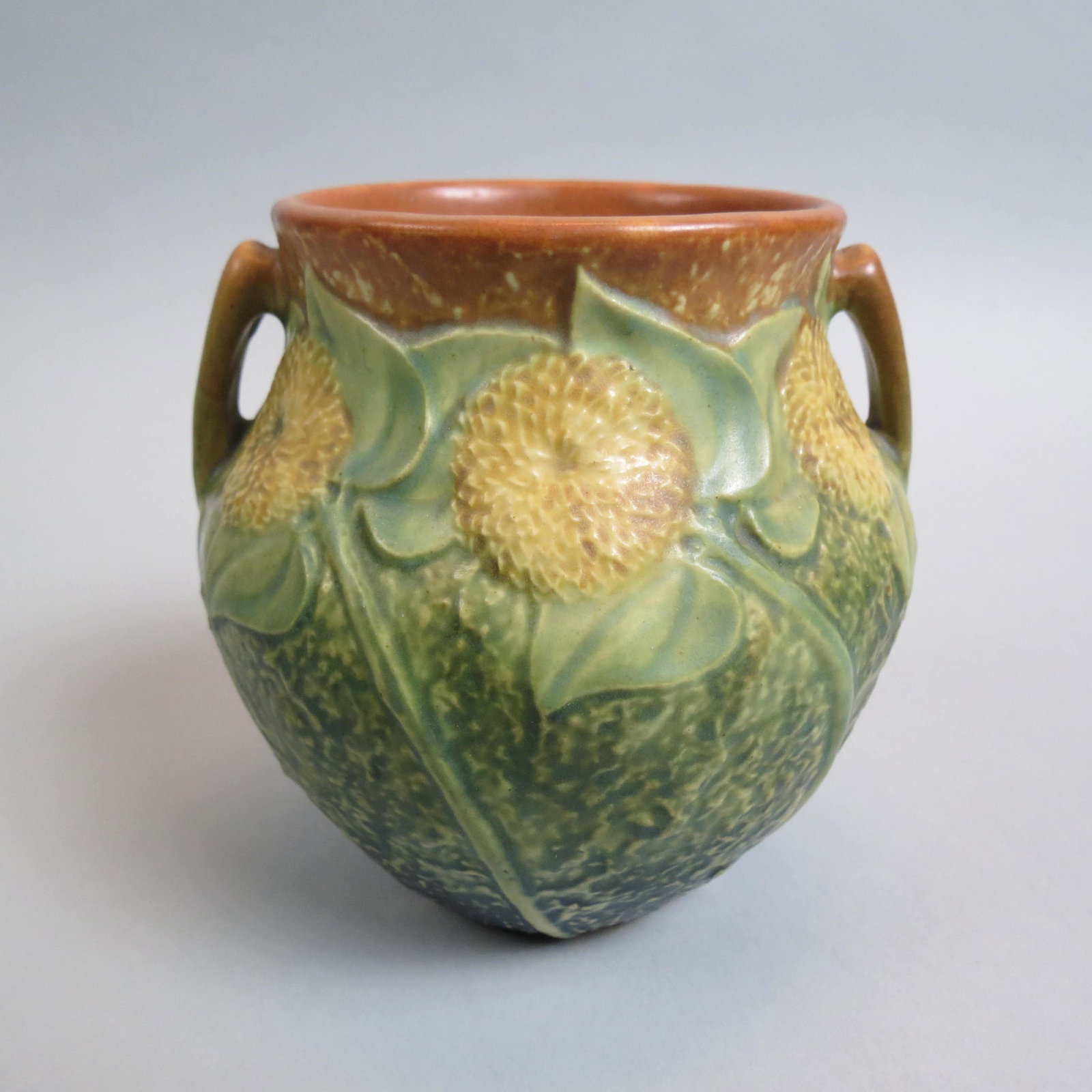 Roseville Pottery "Sunflower" Vase 1930,: handled, 5", excellent.....Sunflower is a middle period pattern introduced by Roseville Pottery in 1930. The pattern's popularity and value rose sharply in the 1990s when it was featured in a major ho