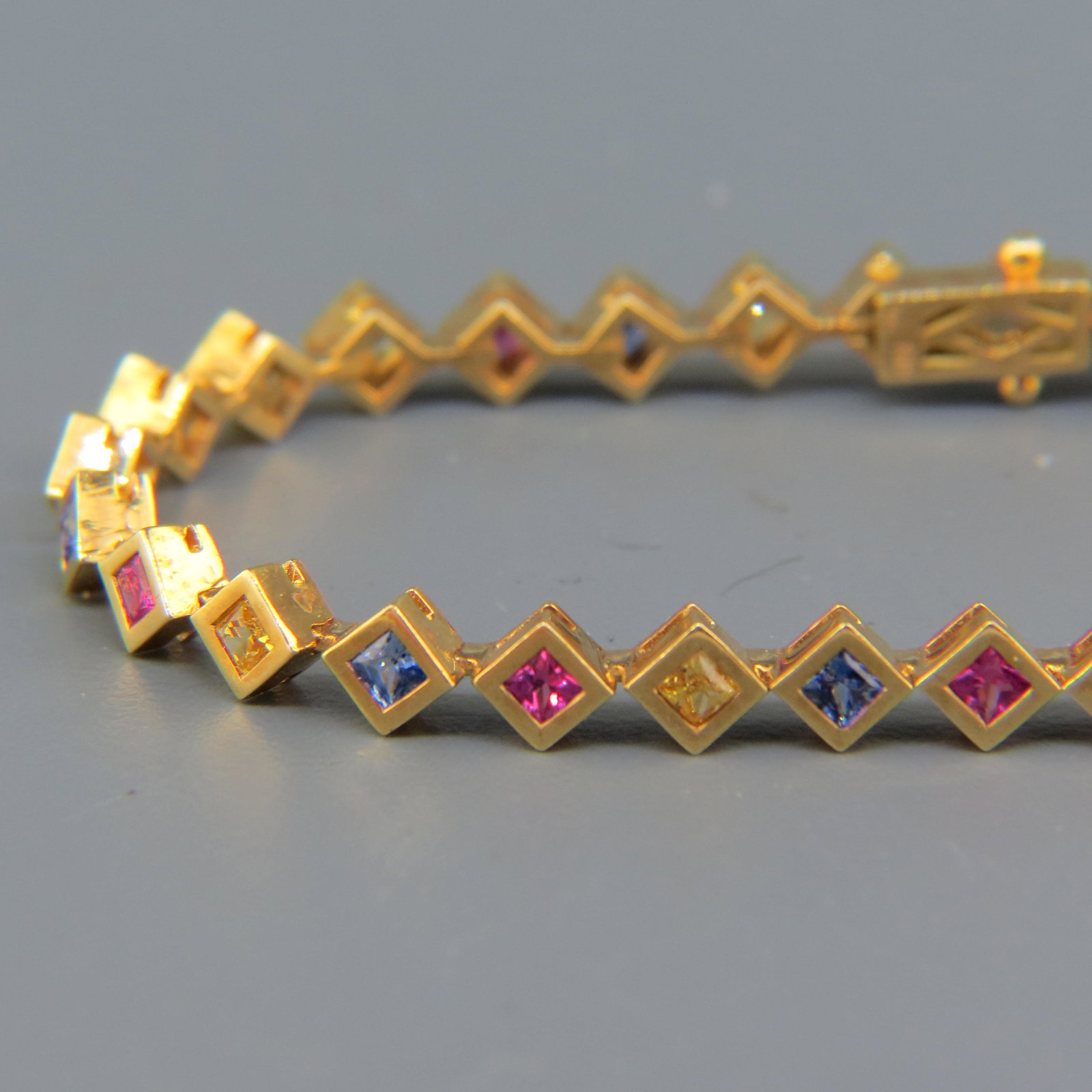 Sapphire & 18K Gold Bracelet with 36 Gemstones: Various colors, square cut, total 5 carats, yellow gold, 17.1 Grams, with appraisal of $3,950.00, 7" Long.
