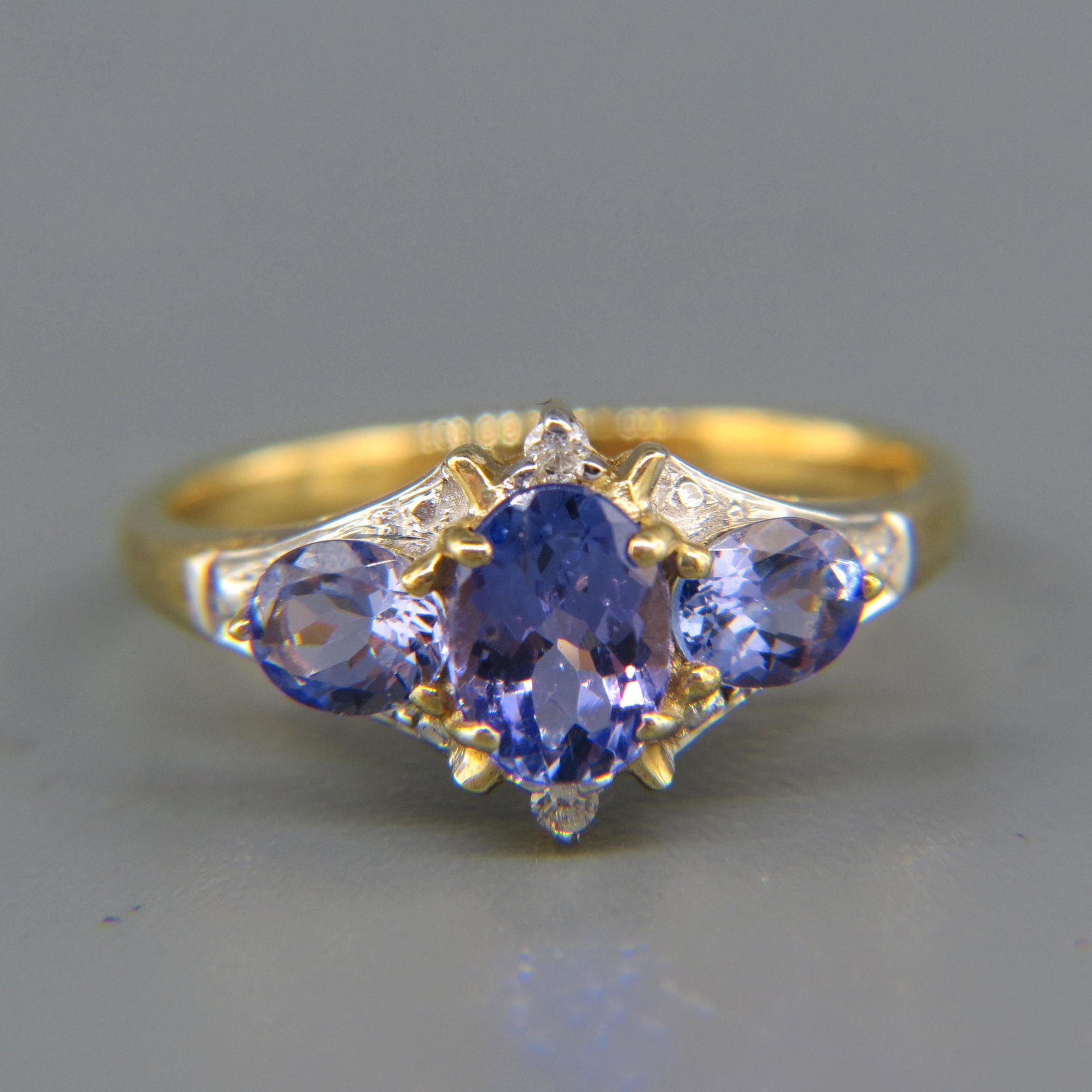 Tanzanite & Diamond Ring: A trio of vivid gems totaling 2 carats and two round diamonds totaling .O3 carat in 14K yellow gold, with appraisal of $1,050.00, Currently size 7.