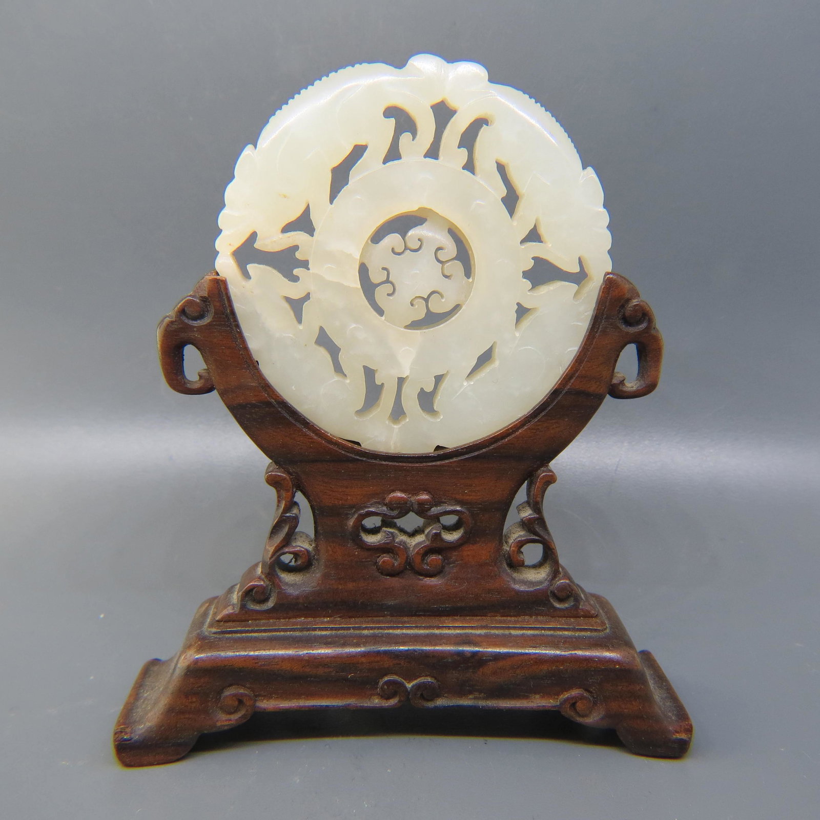 Chinese Carved Jade Medallion with Turning Center: Depicts mythological animals with Buddhist symbol in the turning center, 2 1/4 diameter with original carved wooden stand.