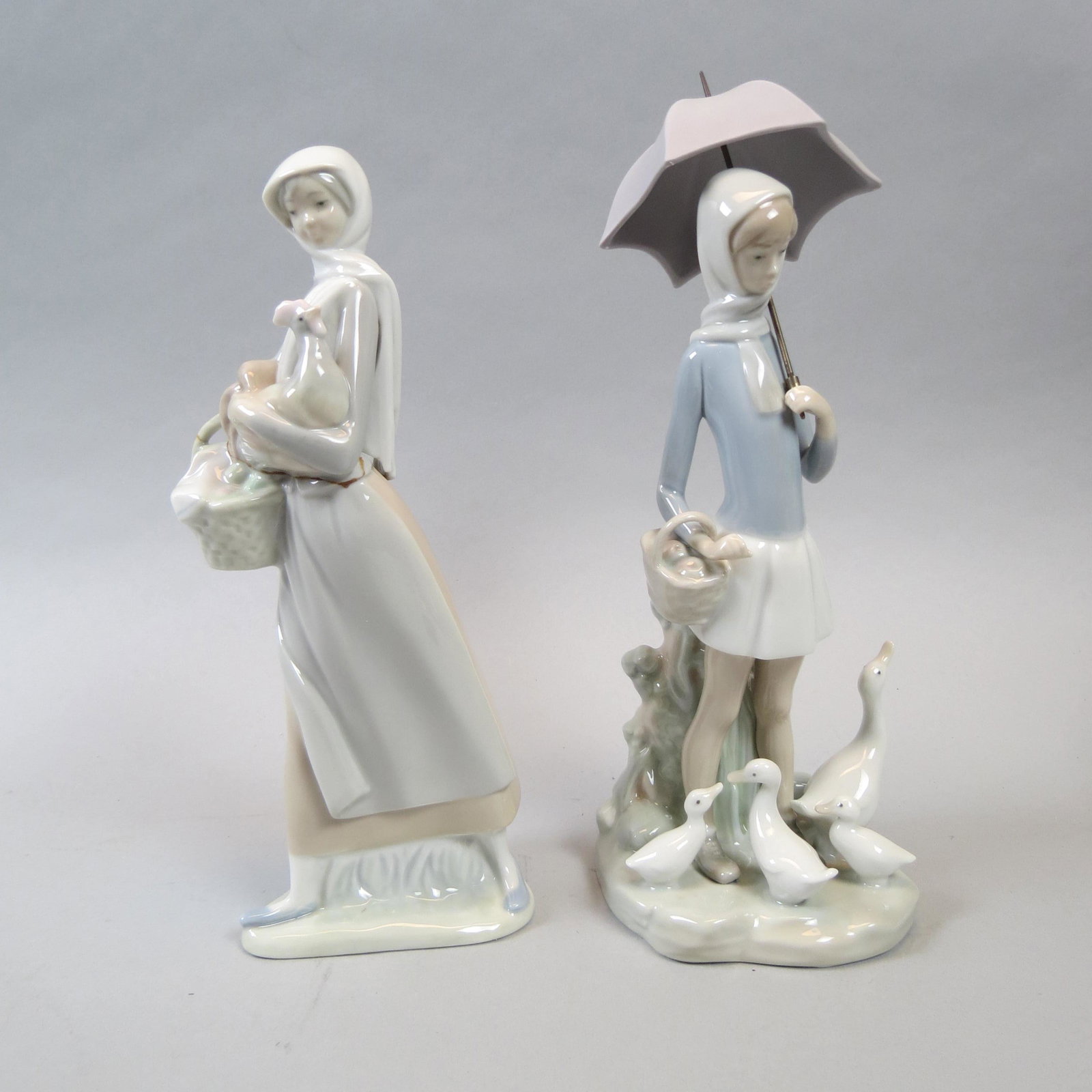 2 Lladro Figurines, girl with rooster & basket: Of eggs, along with girl holding an umbrella, ducks at her feet, 9 1/2 and 11", both excellent.
