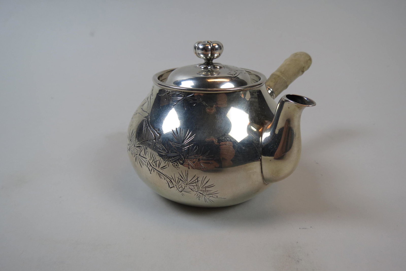 Japanese Silver Miniature Teapot,: or hot water pot, engraved branch and leaf design, 3" tall, 3 1/2" diameter plus carved handle, one repair spot, 134 grams.