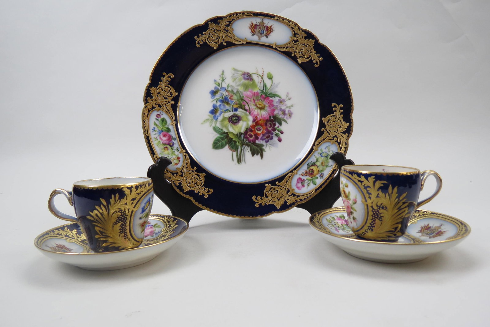 10 Royal Family French Porcelain Cups & Saucers,: hand painted crest and florals, elaborate gold work with rich cobalt trim, together with a matching 9" plate, 19th century, attributed to Sevres, excellent.